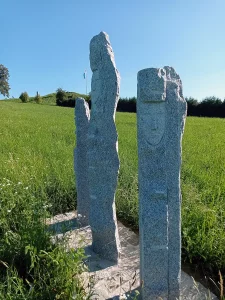 Drei Stehlen aus Granit zeigen jeweils ein Frauengesicht.