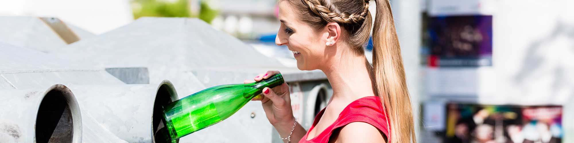 Frau auf Recyclinghof wirft Flaschen in einen Container