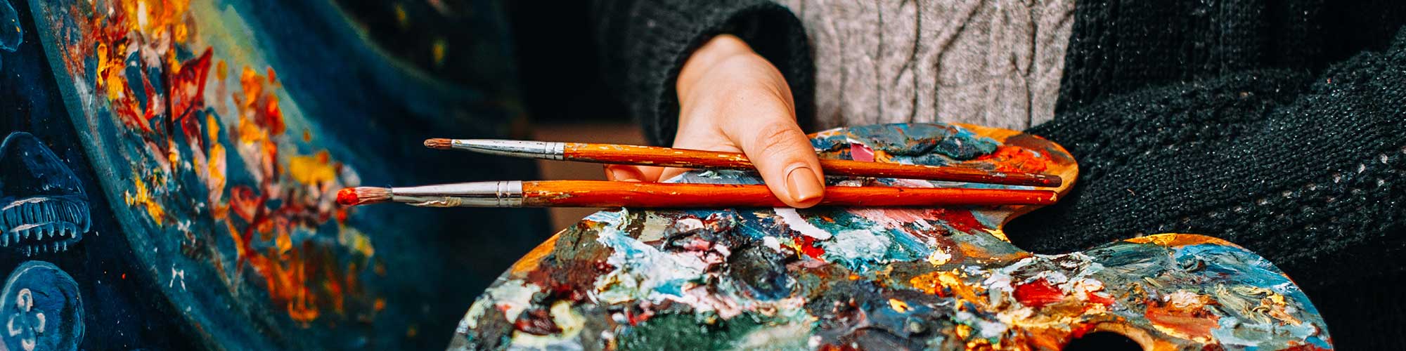 Malerin hält bunte Palette und Pinsel über abstraktem Kunstwerk