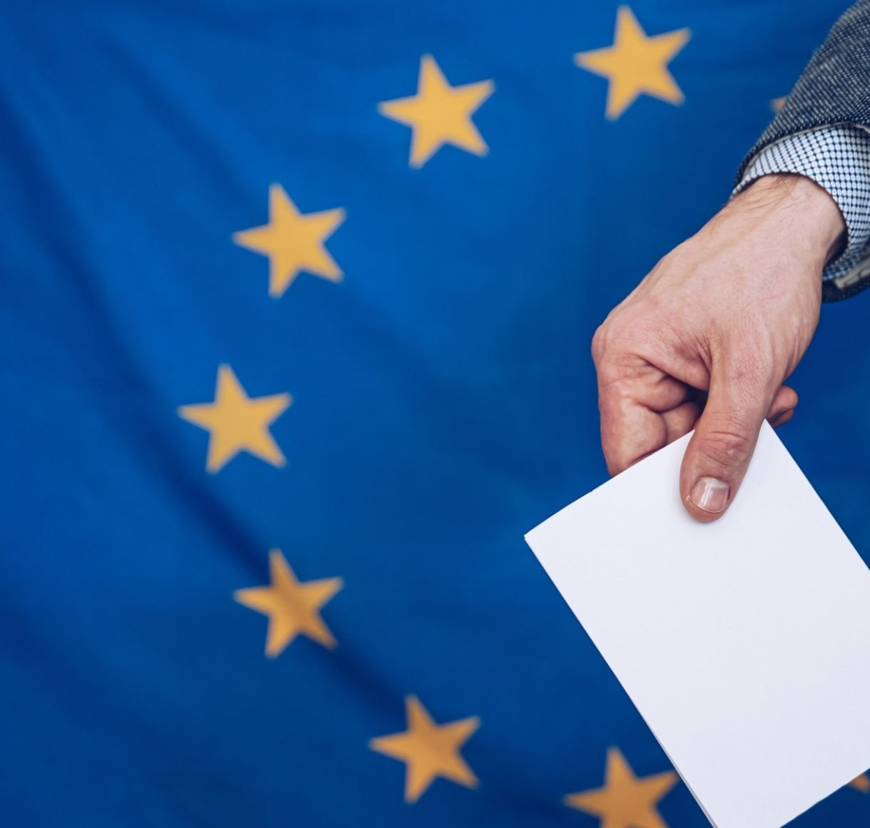Hand mit Wahlzettel vor EU Flagge